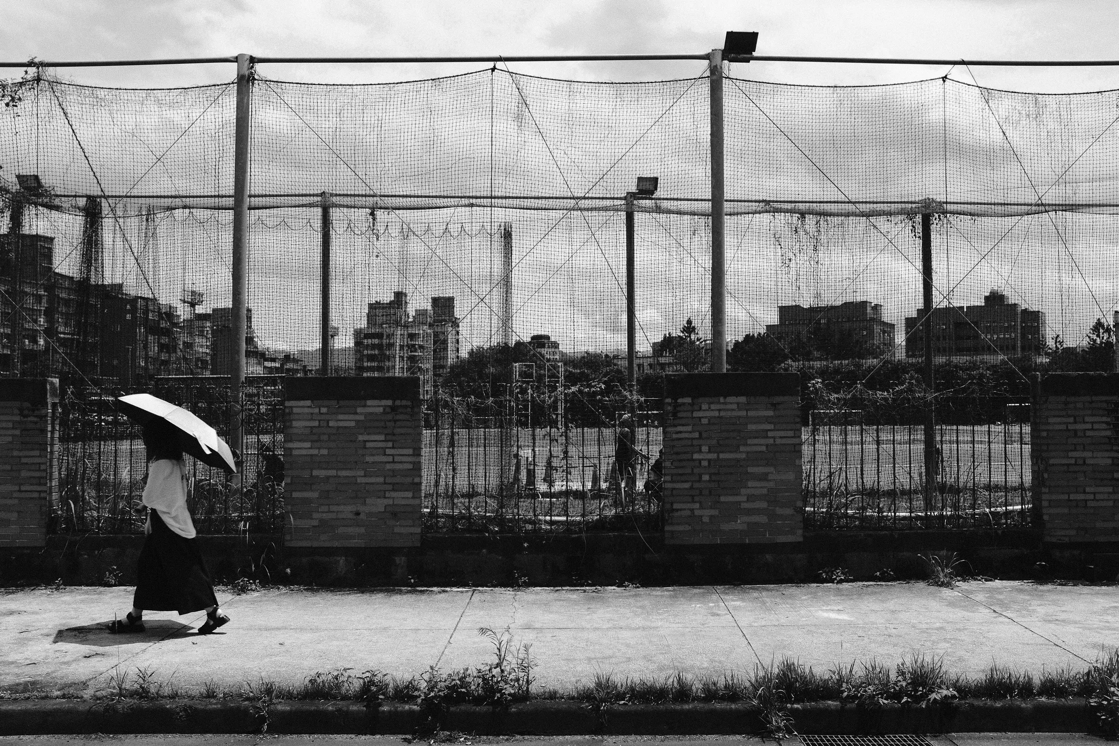 城市圍網前撐傘行人走過空地，365 Project July 22