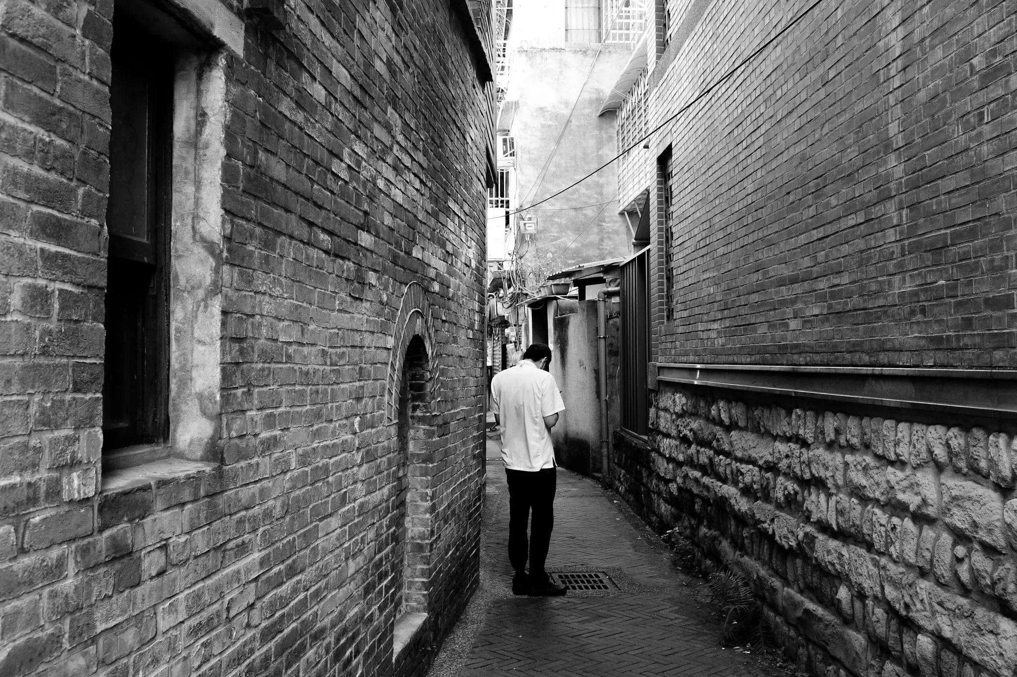 磚牆窄巷中一名男子低頭站在光影交界，365 Project August 19