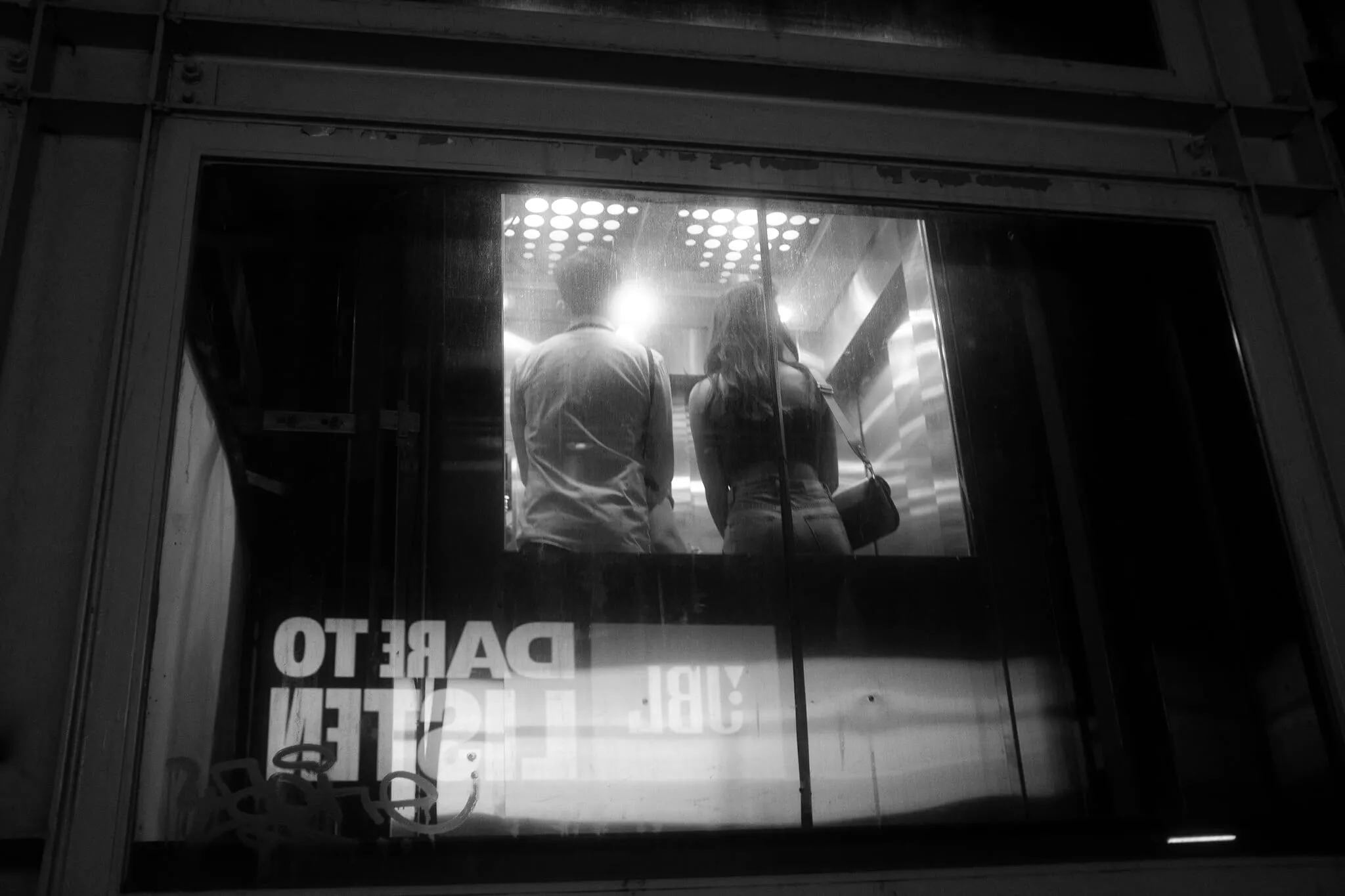 玻璃窗內兩人站在明亮電梯裡的夜間反射，365 Project August 21