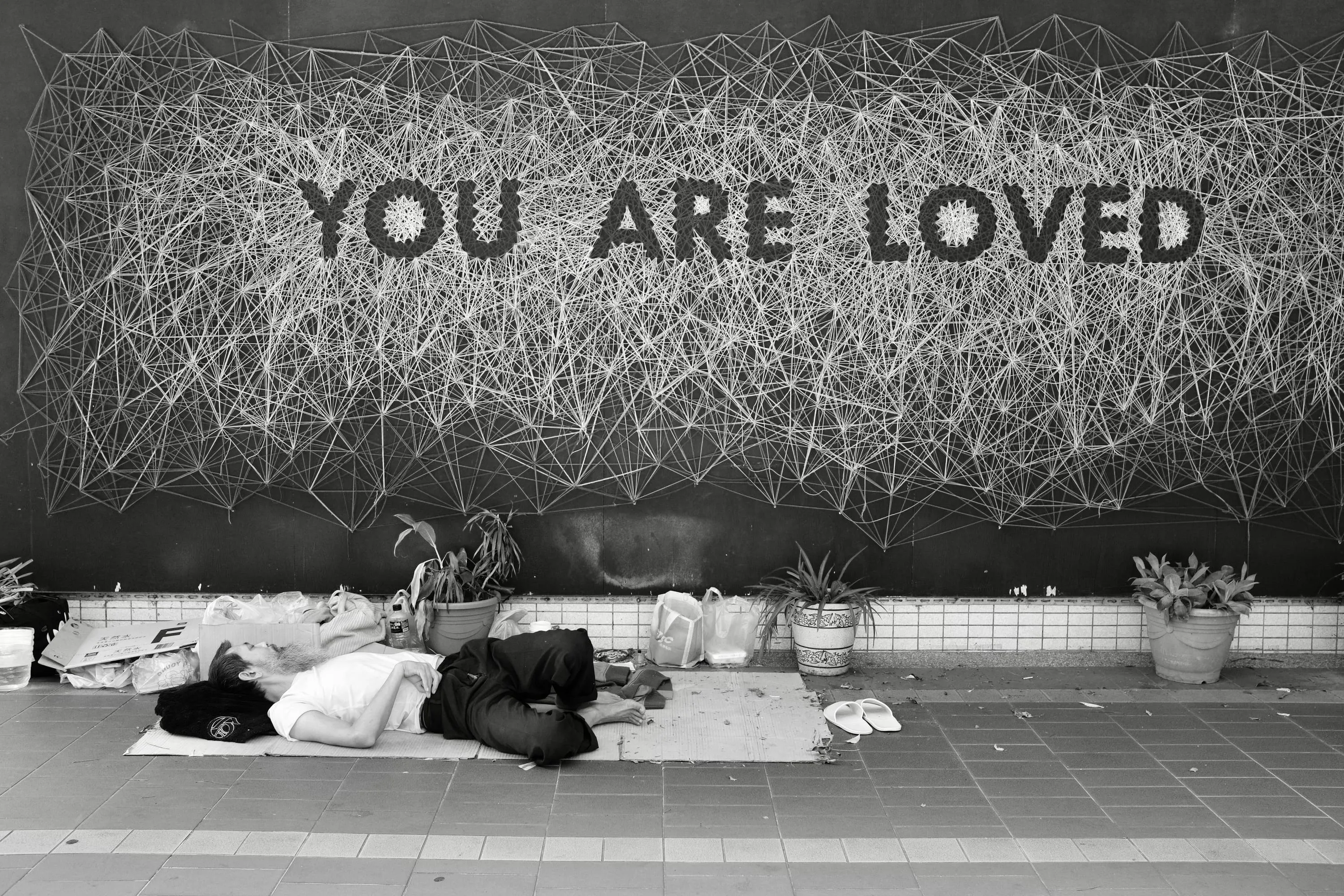 YOU ARE LOVED 文字牆下男子躺在人行道墊子上休息，365 Project September 4