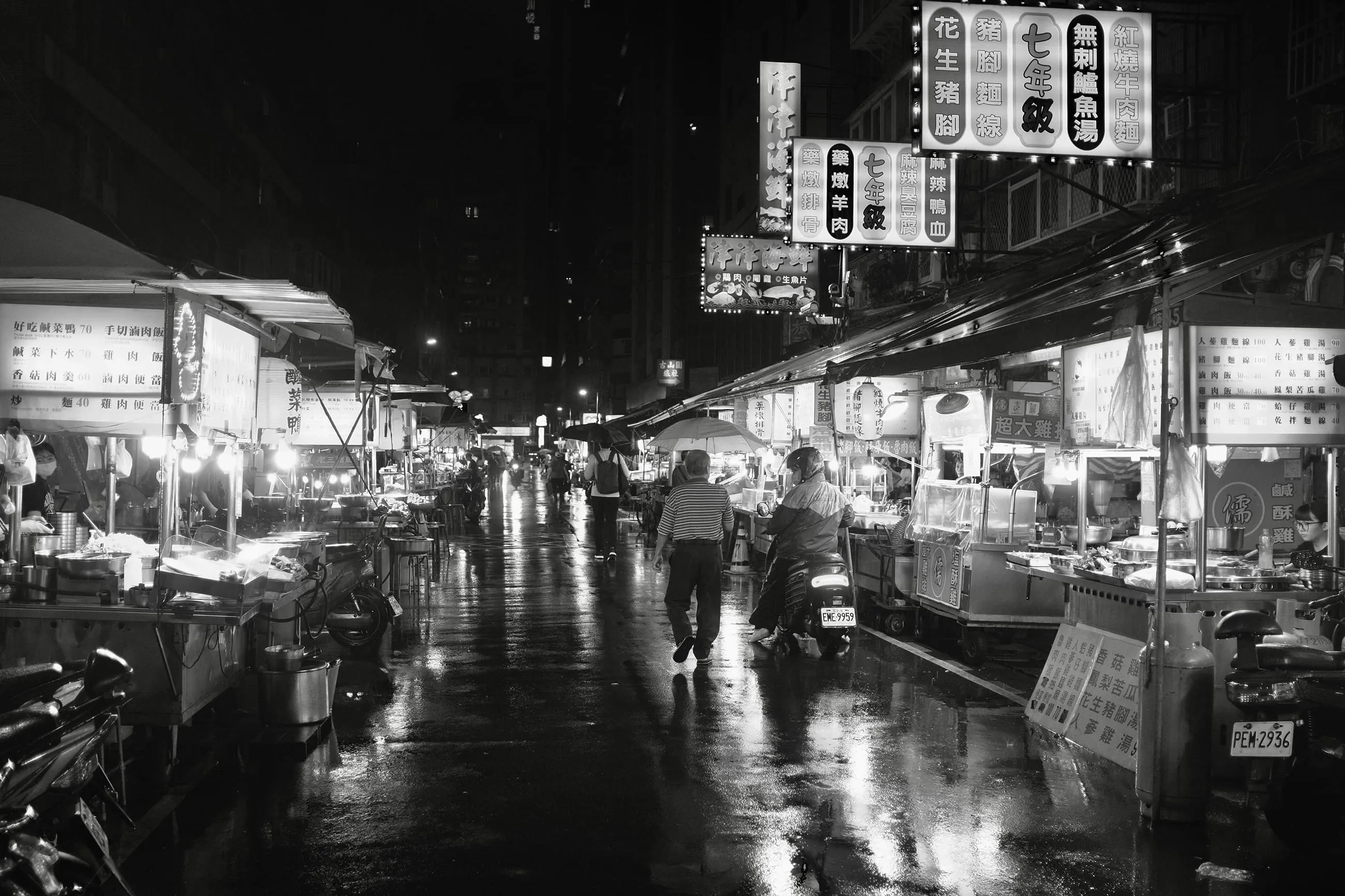 雨夜狹窄街道上兩名行人向前走，兩側攤位燈光映在濕地面，365 Project October 13
