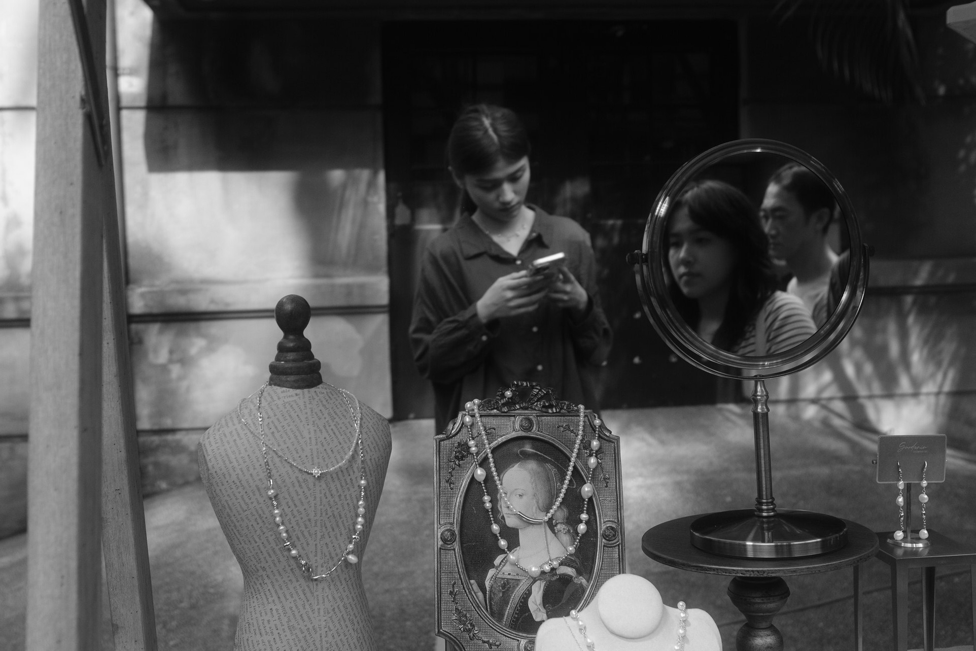 Black and white East District storefront scene with jewelry displays, mirror reflections, and pedestrians passing outside in Taipei