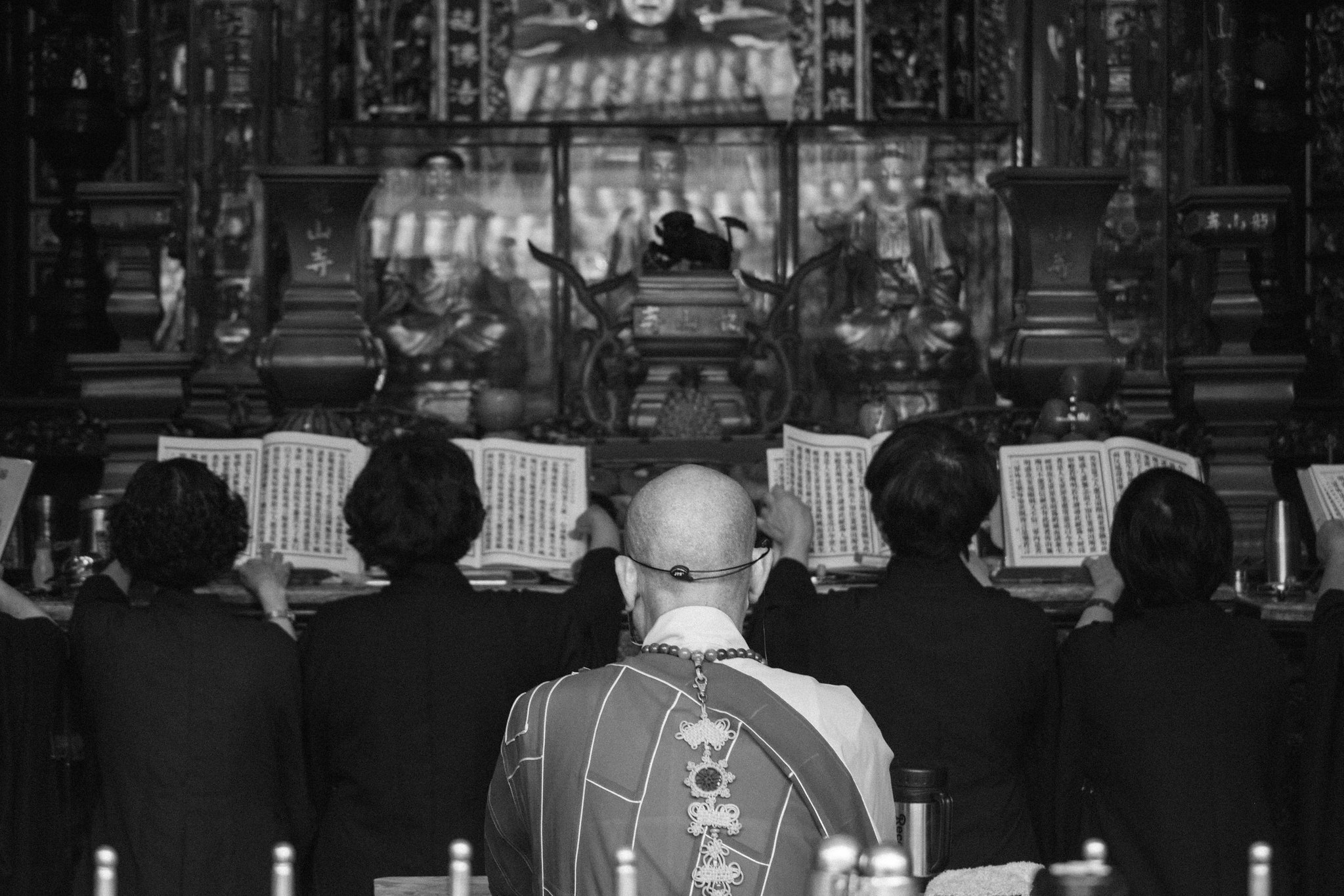Monk and worshippers reading scriptures before an altar during a temple ritual