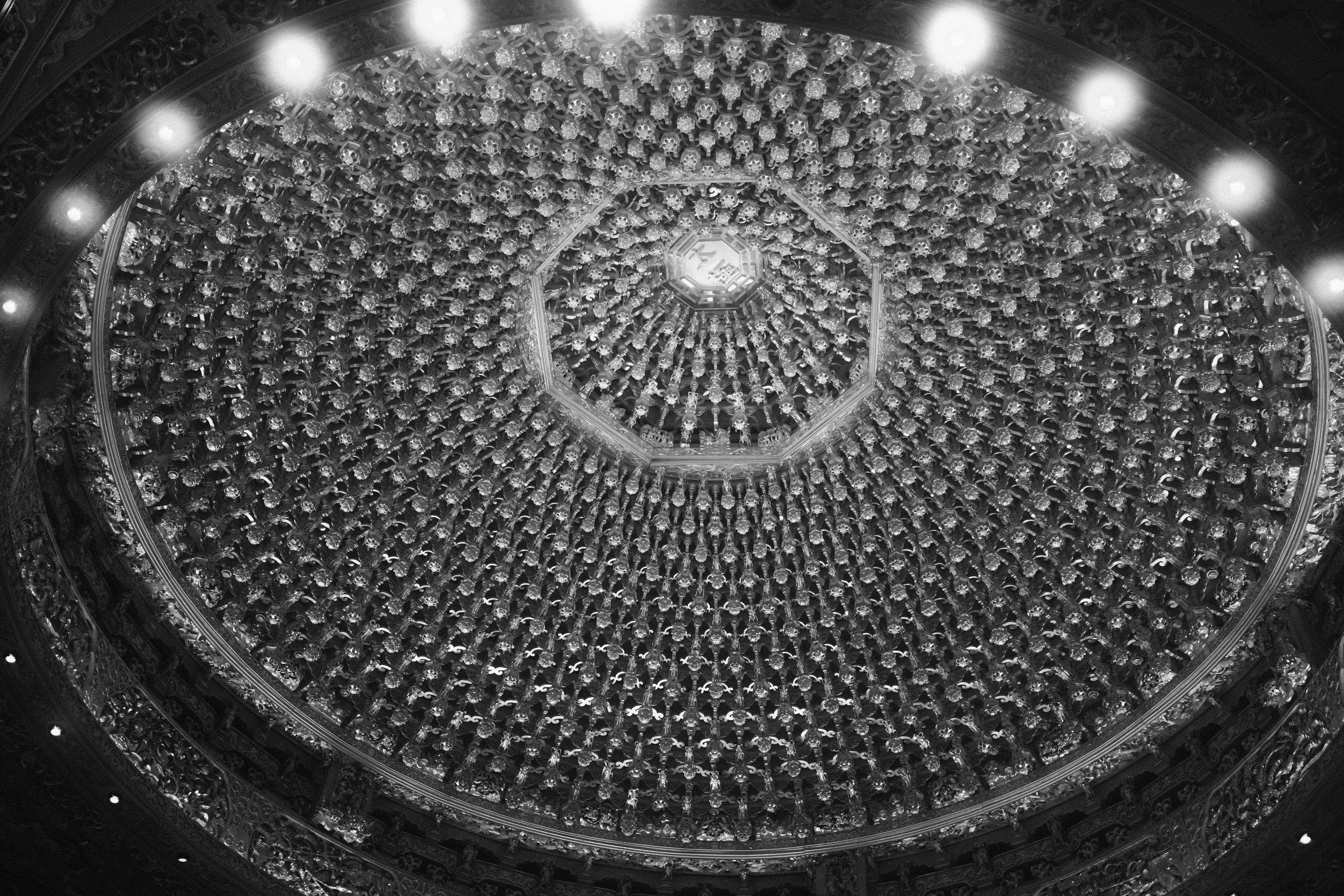 Ornate temple lantern ceiling glowing softly in black and white
