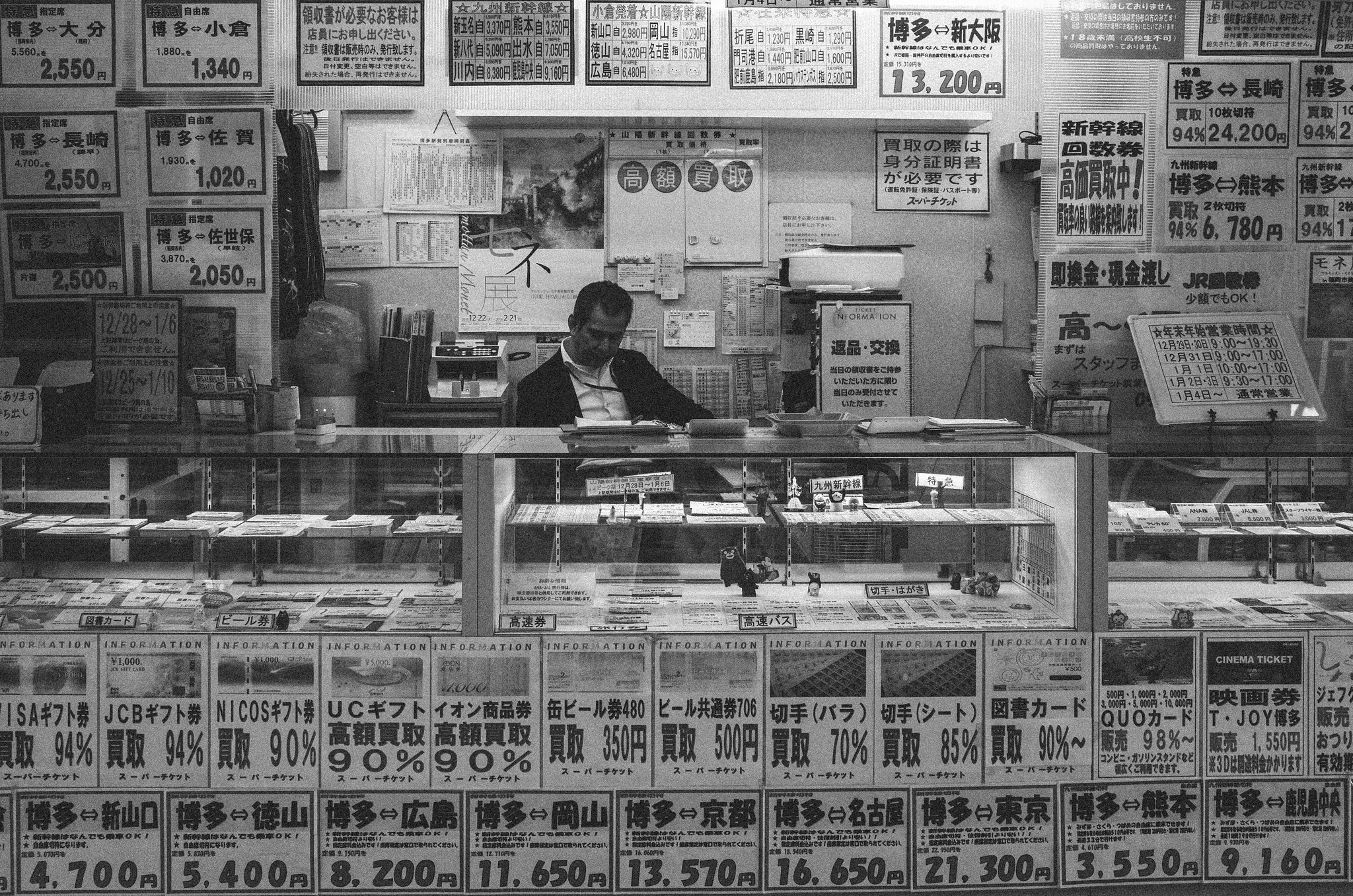 Black and white food counter in Japan with menu boards covering the wall behind the vendor