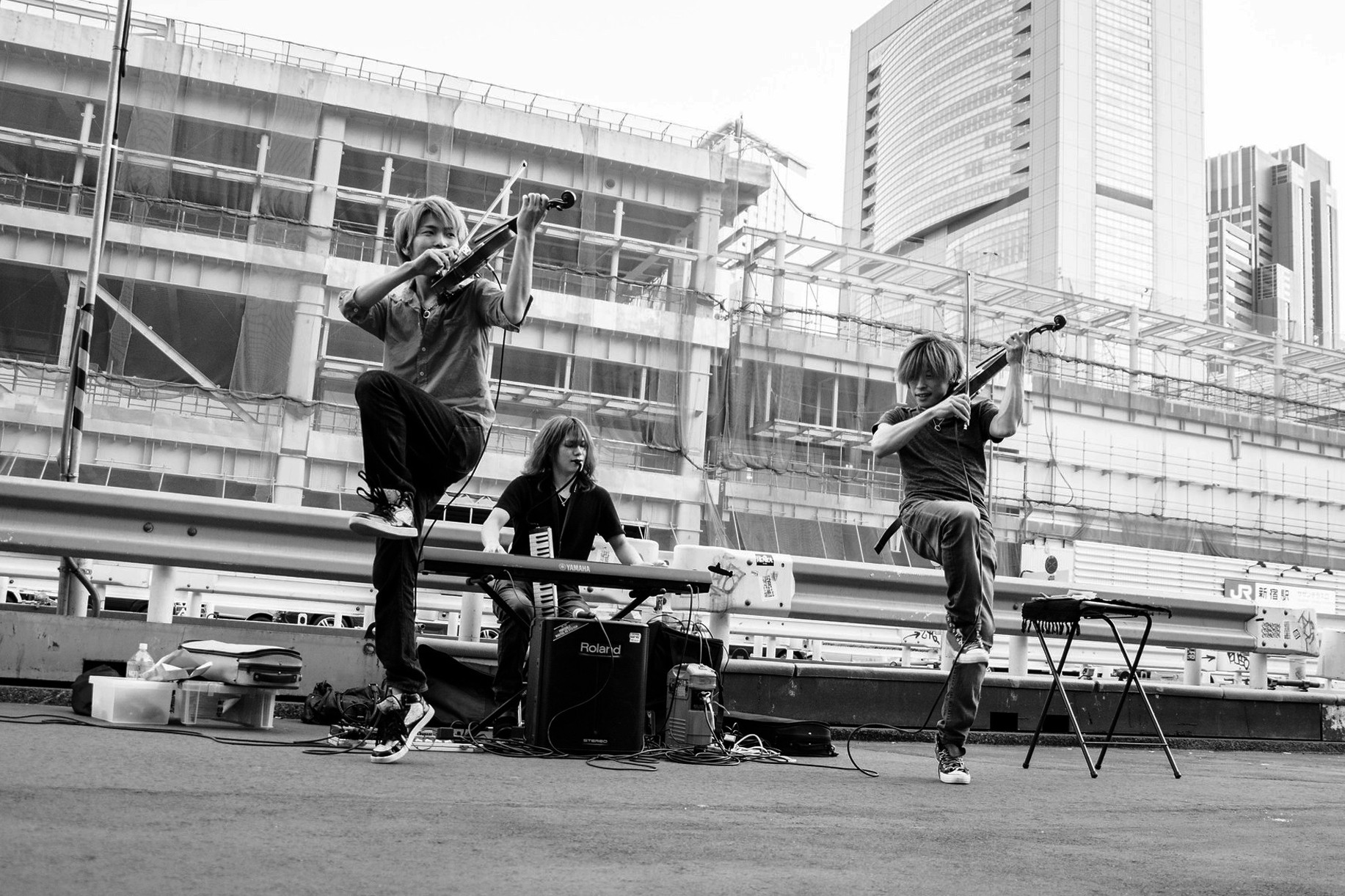 Black and white Japanese street scene with street musicians and violinists performing lively near Shinjuku Station