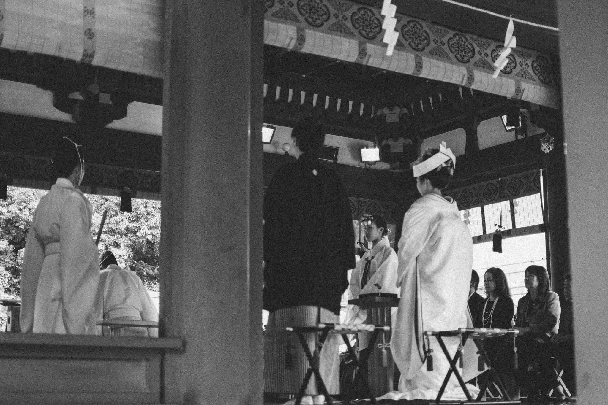 Black and white Shinto wedding ceremony in Japan with attendants gathered beneath a shrine pavilion
