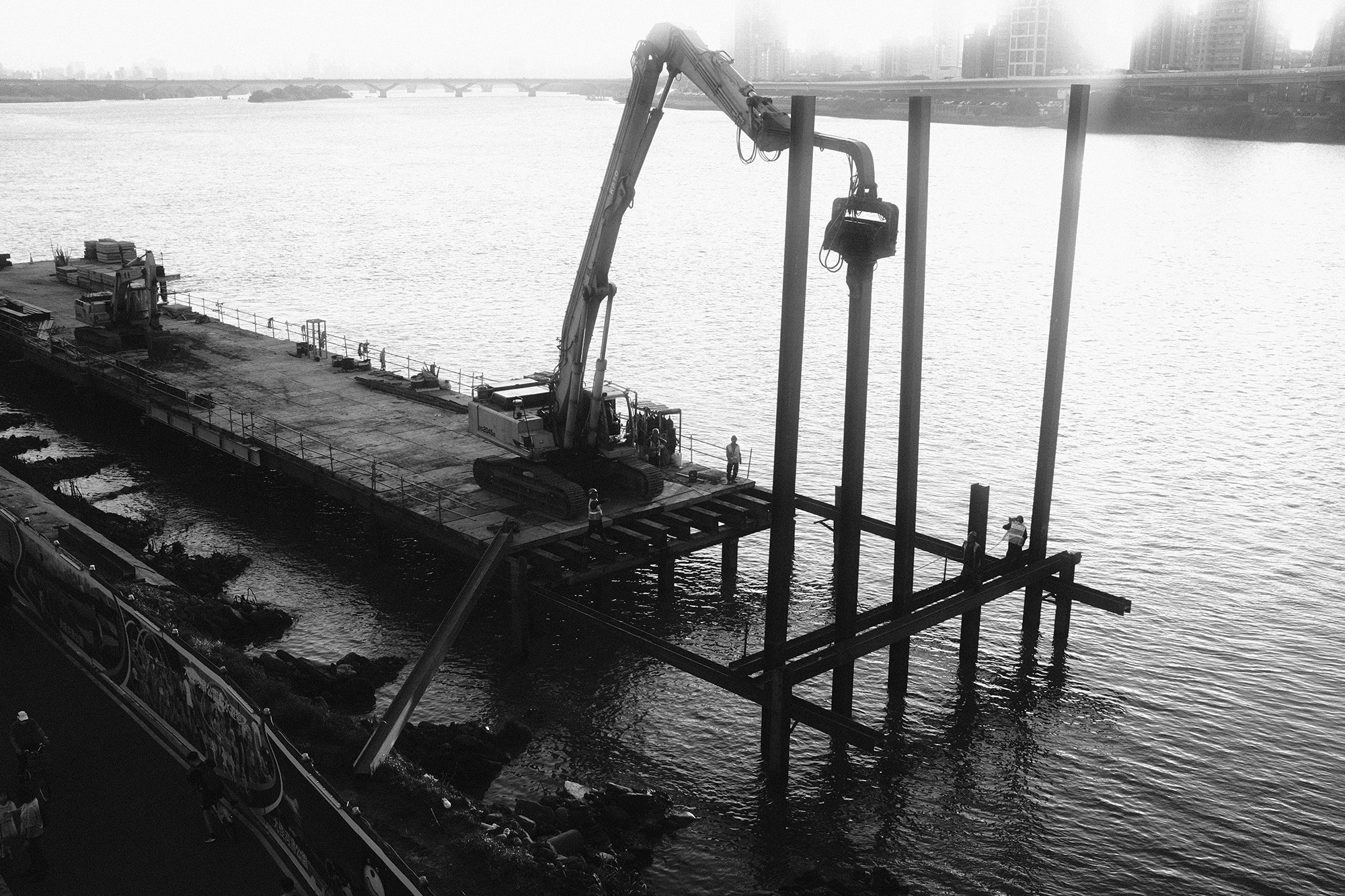 Black and white riverside construction scene showing layered infrastructure and city edges in Taiwan