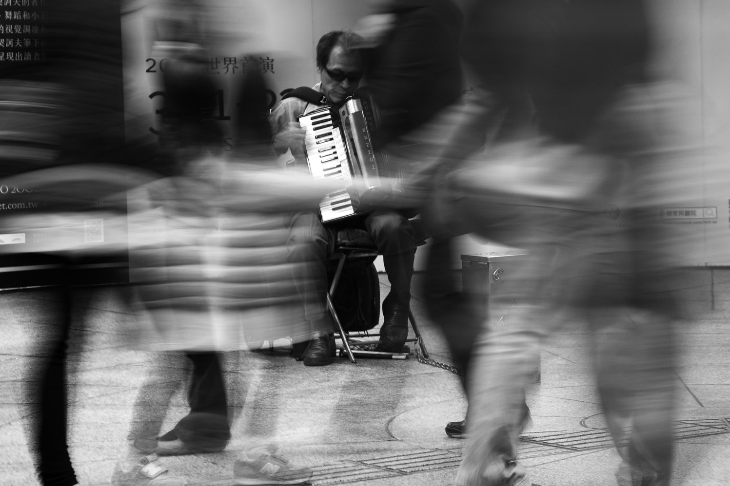 Black and white street photograph of an unaware subject within layered urban surroundings in Taiwan